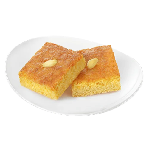 قطعة بسبوسة سميد ذهبية رطبة مع قطر حلو وحبة جوز هند أو فستق فوقها